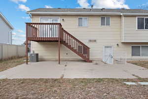 Back of house with central air condition unit, a shingled roof, fence, stairway, and a patio area