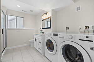 Clothes washing area featuring laundry area, visible vents, and washer and clothes dryer