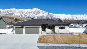 View of front facade with concrete driveway, an attached garage, fence, and a mountain view