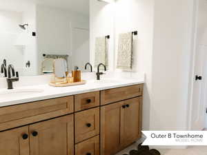 Full bath featuring tiled shower, a sink, and double vanity