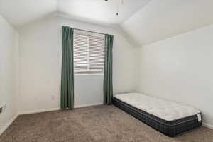 Bedroom featuring lofted ceiling, carpet flooring, and baseboards