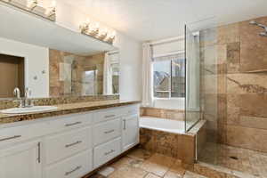 Bathroom with a bath, a stall shower, stone tile flooring, and vanity
