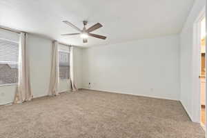 Empty room featuring light carpet, ceiling fan, and baseboards
