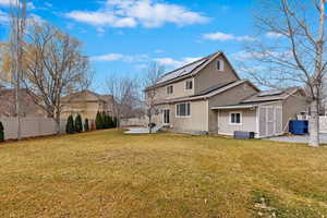 Back of property with a patio, a lawn, a fenced backyard, and roof mounted solar panels