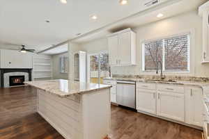 Kitchen with visible vents, dark wood-style flooring, stainless steel dishwasher, a fireplace, and a sink