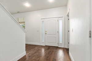 Entrance foyer featuring dark wood-style floors, visible vents, and baseboards
