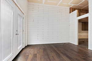 Unfurnished room featuring dark wood-style flooring and wooden walls