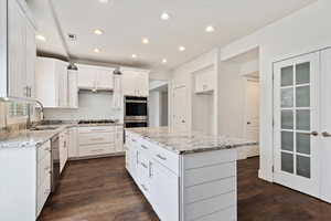 Kitchen with dark wood-type flooring, a sink, visible vents, white cabinets, and appliances with stainless steel finishes