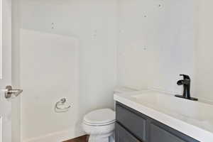 Half bathroom with vanity, toilet, and baseboards