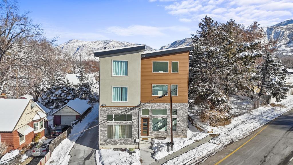 Snow covered property featuring stone siding, a mountain view, and stucco siding