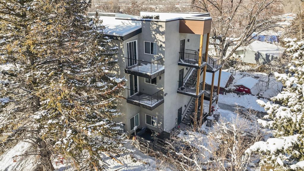 View of snow covered exterior with stairway and stucco siding