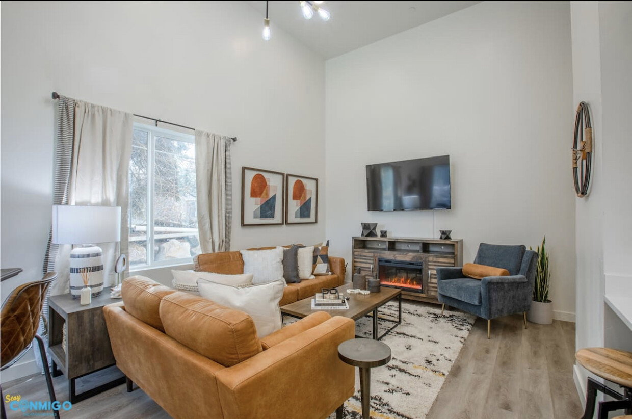 Living area featuring high vaulted ceiling, a fireplace, baseboards, and wood finished floors
