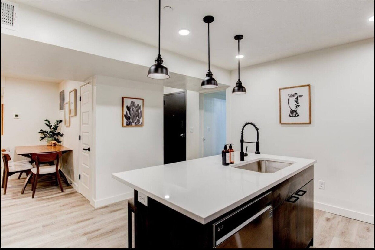 Kitchen featuring light wood finished floors, light countertops, visible vents, a sink, and dishwasher