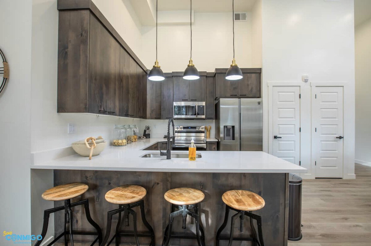 Kitchen with stainless steel appliances, a sink, visible vents, dark brown cabinets, and light countertops