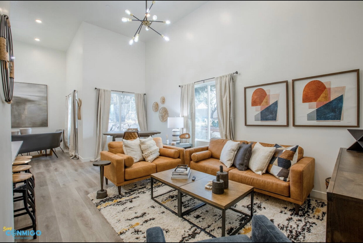 Living area featuring a notable chandelier, recessed lighting, a high ceiling, wood finished floors, and baseboards