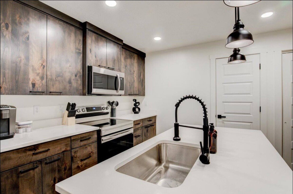 Kitchen with dark brown cabinets, stainless steel appliances, a sink, and light countertops
