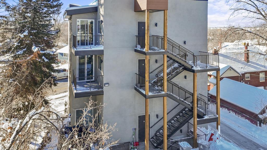 Snow covered property featuring stairs and stucco siding