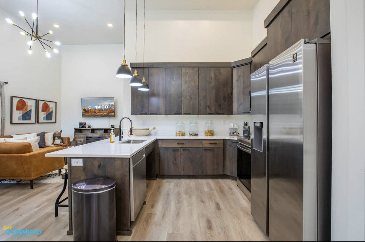 Kitchen with stainless steel appliances, open floor plan, a sink, dark brown cabinetry, and a peninsula