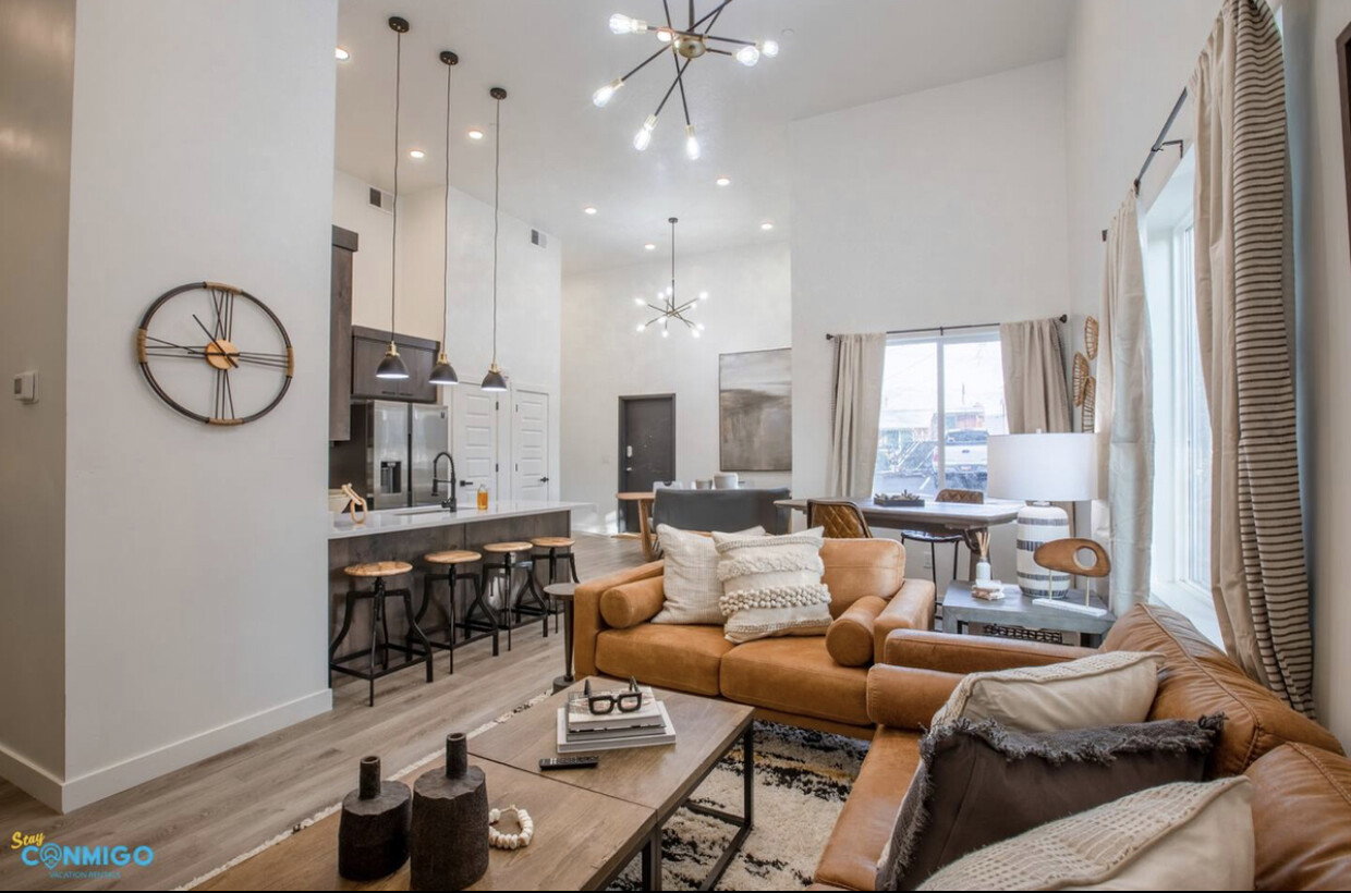 Living area with a chandelier, visible vents, baseboards, a towering ceiling, and light wood-style floors