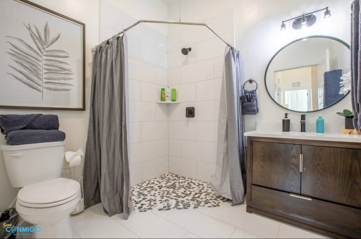 Bathroom featuring tiled shower, vanity, and toilet