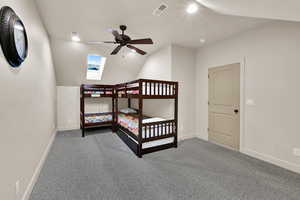 Bedroom featuring a skylight, light carpet, ceiling fan, and lofted ceiling
