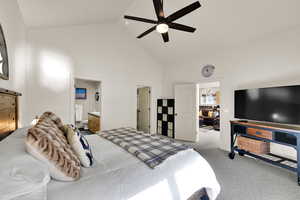 Bedroom with high vaulted ceiling, light colored carpet, connected bathroom, and ceiling fan