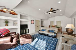 Carpeted living room featuring built in shelves, lofted ceiling, recessed lighting, and ceiling fan