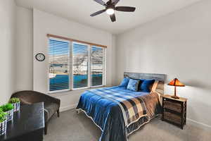Carpeted bedroom with a ceiling fan and baseboards