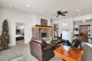 Living area with a fireplace, light colored carpet, a ceiling fan, recessed lighting, and stairway