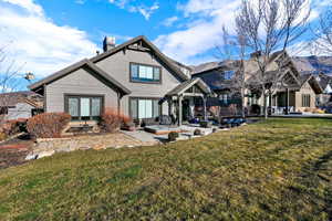 Rear view of house featuring a patio area, a lawn, and a chimney