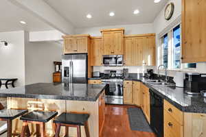 Kitchen featuring light brown cabinetry, tile counters, a kitchen breakfast bar, stainless steel appliances, and a center island