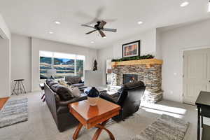 Living area featuring a ceiling fan, a fireplace, recessed lighting, and light colored carpet