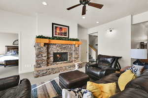 Carpeted living area with a ceiling fan, a stone fireplace, recessed lighting, and stairway