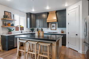 Kitchen with open shelves, custom range hood, appliances with stainless steel finishes.