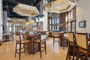 Dining area with a community bar, light wood finished floors, and a towering ceiling