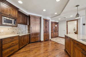 Kitchen with a sink, visible vents, decorative backsplash, light wood finished floors, and stainless steel microwave