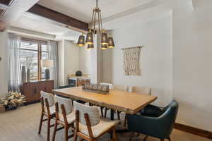 Dining area with light carpet, beamed ceiling, and baseboards