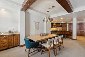 Dining space with baseboards, light colored carpet, beam ceiling, indoor wet bar, and recessed lighting