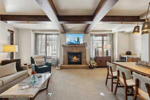 Living room with a glass covered fireplace, beam ceiling, and plenty of natural light