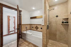 Full bathroom featuring a stall shower, stone tile flooring, a bath, and tile walls