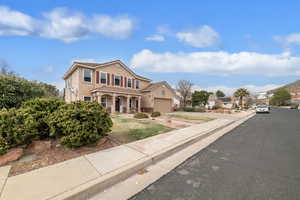 Traditional-style home with stucco siding, an attached garage, concrete driveway, and a porch