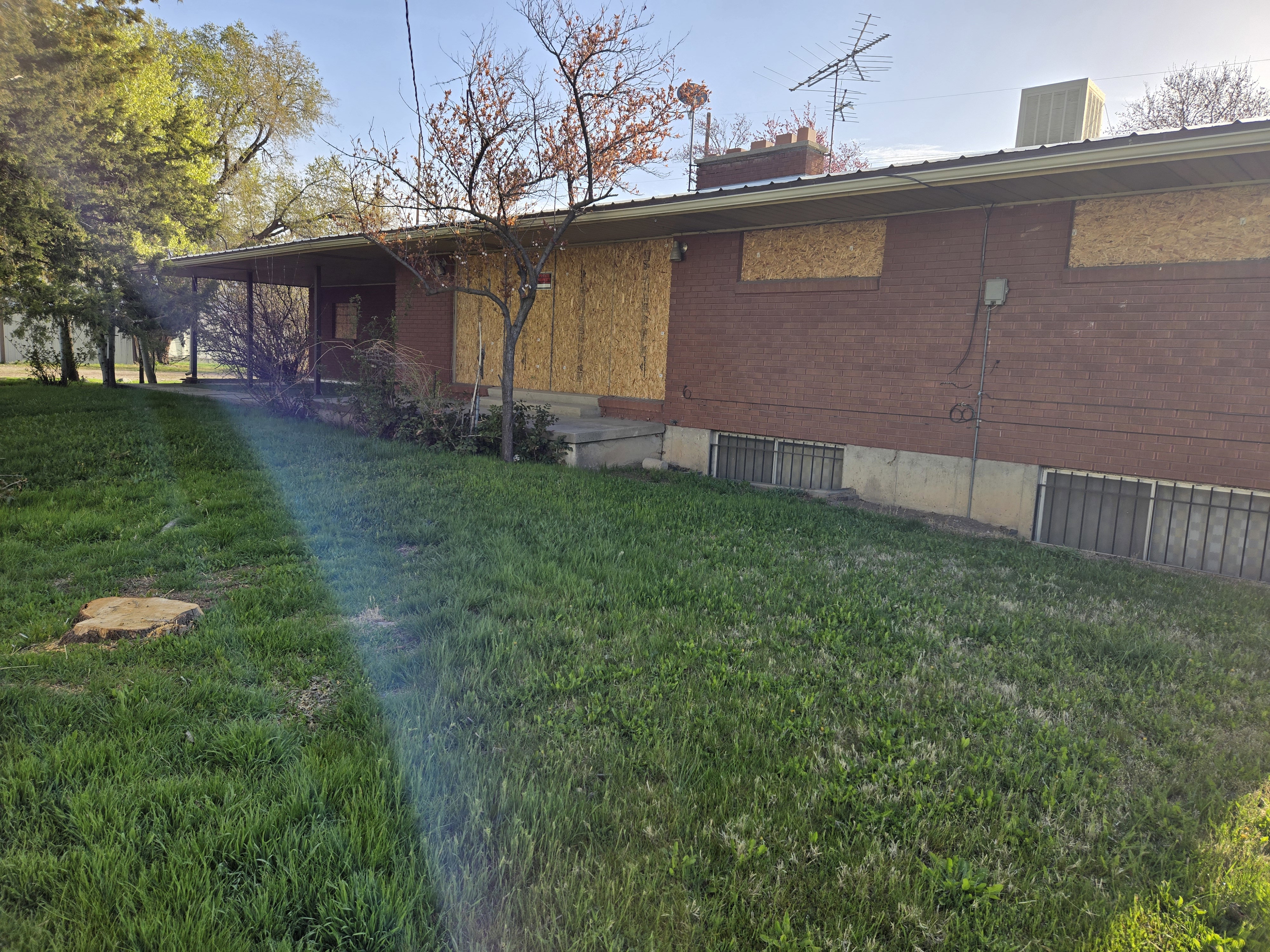 View of property exterior featuring brick siding, a chimney, and a lawn