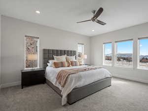 Bedroom featuring light carpet, a ceiling fan, and baseboards