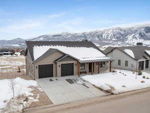 View of front of house featuring a garage, driveway, covered porch, a mountain view, and board and batten siding