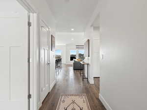 Hall with dark wood-type flooring, recessed lighting, and baseboards