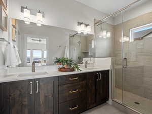 Bathroom with double vanity, a stall shower, and a sink