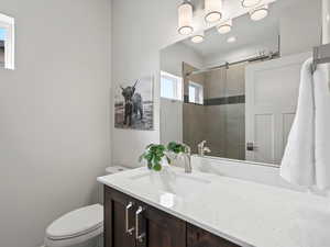 Bathroom featuring toilet, tiled shower, and vanity