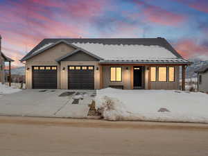 View of front of home featuring board and batten siding, concrete driveway, an attached garage, and a standing seam roof