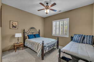 Carpeted bedroom with a ceiling fan, visible vents, and baseboards