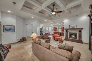 Living area featuring arched walkways, a fireplace, coffered ceiling, and visible vents